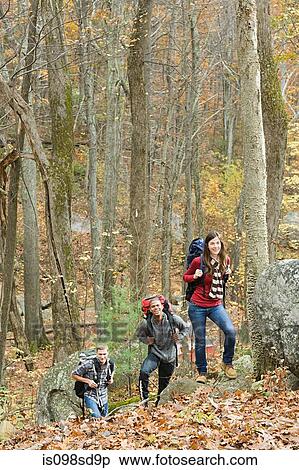 Stock Photography - Young people hiking through forest. Fotosearch