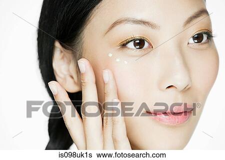 Stock Photograph - Young woman applying eye cream. Fotosearch