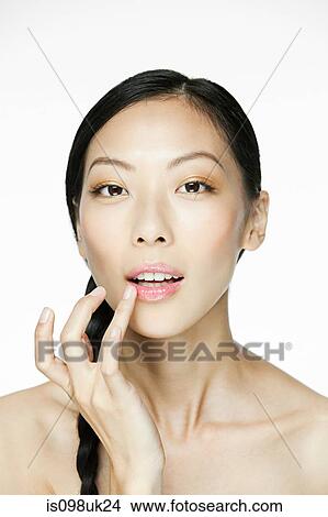 Picture - Young woman applying lipgloss. Fotosearch