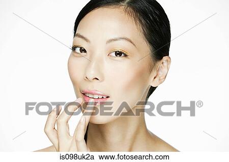 Stock Image - Young woman applying lipgloss. Fotosearch