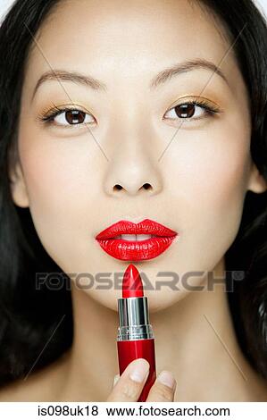 Stock Photo - Young woman applying red lipstick. Fotosearch