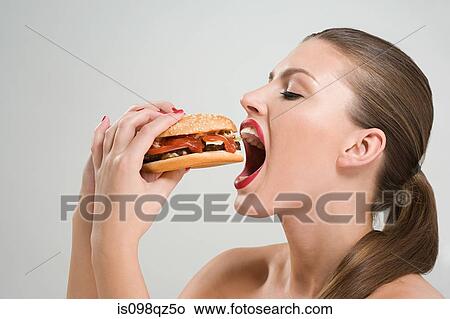 Picture - Young woman eating a burger. Fotosearch