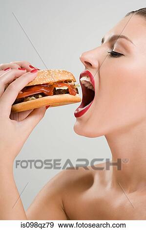 Young woman eating a hamburger View Large Photo Image Stock Photo - Young woman eating a hamburger. Fotosearch