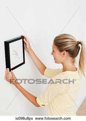 Young woman hanging picture on wall View Large Photo Image Stock Photograph - Young woman hanging picture on wall. Fotosearch