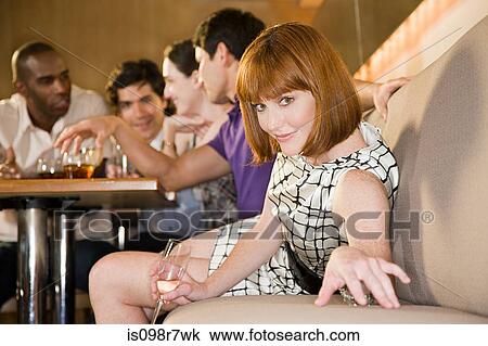 Stock Image - Young woman in a bar with friends. Fotosearch