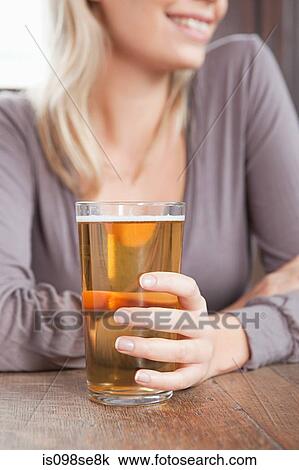 Young woman in bar holding pint of beer View Large Photo Image Stock Image - Young woman in bar holding pint of beer. Fotosearch