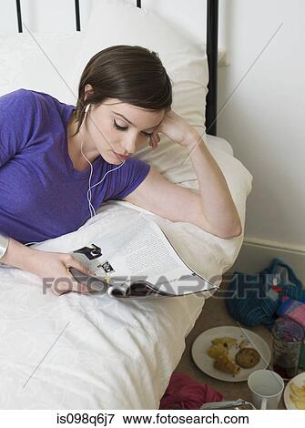 Young woman listening to music and reading a magazine View Large Photo Image Stock Photo - Young woman listening to music and reading a magazine. Fotosearch