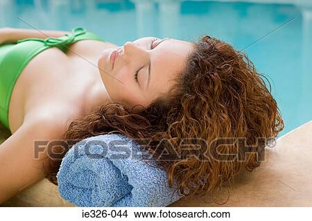 Picture - Young woman lying by pool. Fotosearch
