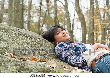 Stock Photography - Young woman lying on stone. Fotosearch