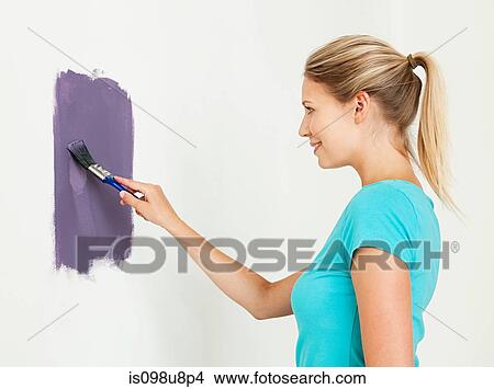 Picture - Young woman painting a wall. Fotosearch