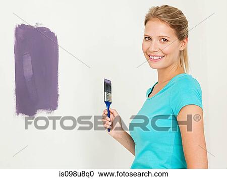 Young woman painting a wall View Large Photo Image Stock Image - Young woman painting a wall. Fotosearch