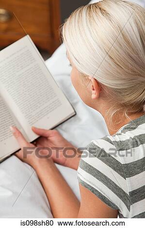 Stock Image - Young woman reading book, high angle. Fotosearch