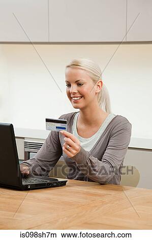 Young woman sitting at table with laptop View Large Photo Image Picture - Young woman sitting at table with laptop. Fotosearch