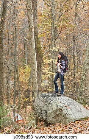 Young woman standing on stone in forest View Large Photo Image Stock Image - Young woman standing on stone in forest. Fotosearch
