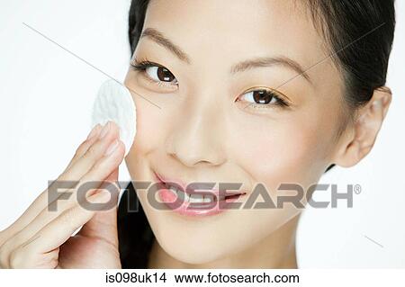 Young woman using cotton pad on face View Large Photo Image Picture - Young woman using cotton pad on face. Fotosearch