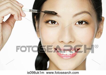 Picture - Young woman using eyebrow comb. Fotosearch