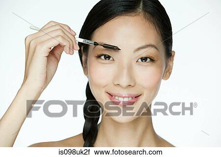 Stock Image - Young woman using eyebrow comb. Fotosearch