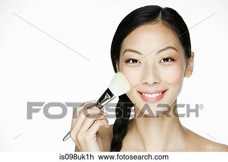 Stock Image - Young woman using makeup brush. Fotosearch