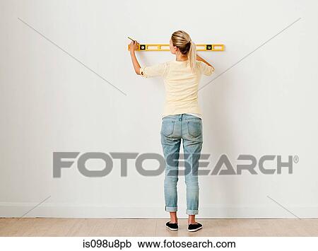 Young woman using spirit level on wall View Large Photo Image Stock Image - Young woman using spirit level on wall. Fotosearch