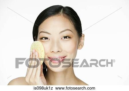 Stock Photo - Young woman using sponge on face. Fotosearch
