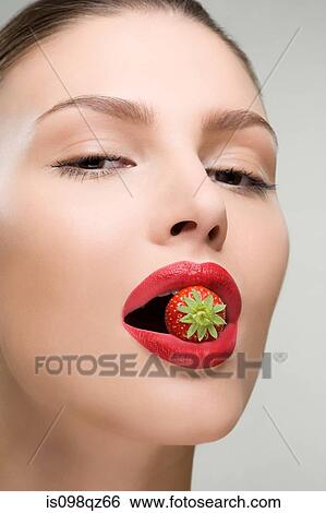 Young woman with a strawberry in her mouth View Large Photo Image Stock Photograph - Young woman with a strawberry in her mouth. Fotosearch