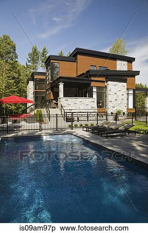 Stock Photography - Beige stone and wood modern house with garden swimming pool. Fotosearch
