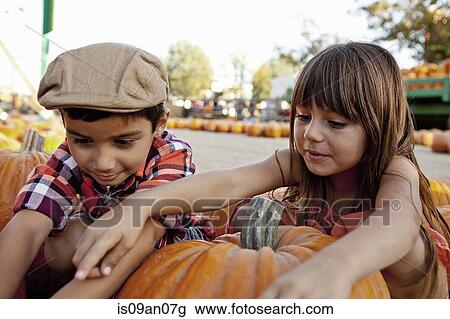 Boy and girl reaching for pumpkins in farmyard View Large Photo Image Stock Image - Boy and girl reaching for pumpkins in farmyard. Fotosearch