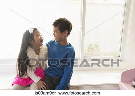 Brother and sister sitting on window seat View Large Photo Image Stock Photography - Brother and sister sitting on window seat. Fotosearch