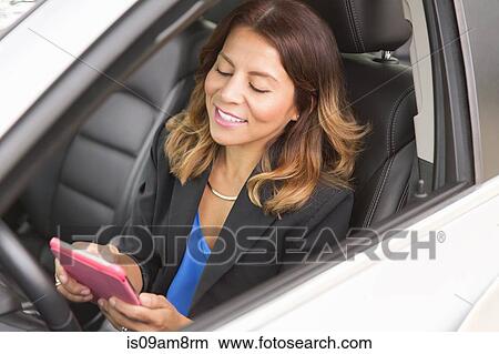 Picture - Business woman using smartphone in car. Fotosearch