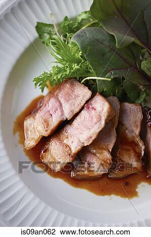 Stock Image - Close up of plate with sliced meat and lettuce garnish. Fotosearch