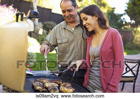 Stock Photography - Father and daughter at barbecue grill in garden. Fotosearch