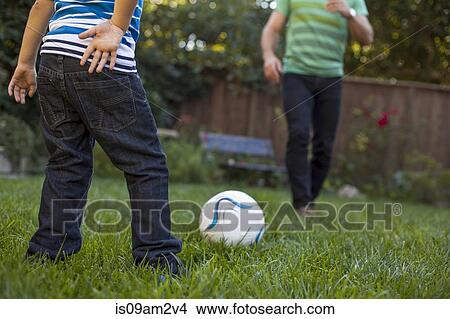 Picture - Father and son playing football in garden. Fotosearch