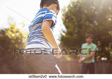 Stock Image - Father and son playing football in garden. Fotosearch