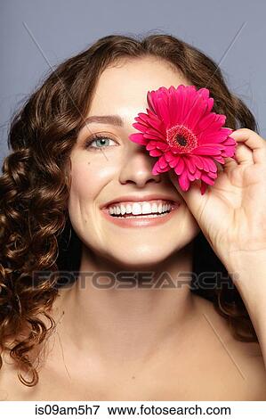Female model covering eye with flower View Large Photo Image Stock Photo - Female model covering eye with flower. Fotosearch