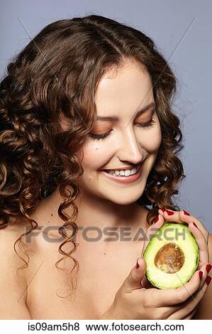 Female model holding halved avocado View Large Photo Image Stock Photo - Female model holding halved avocado. Fotosearch