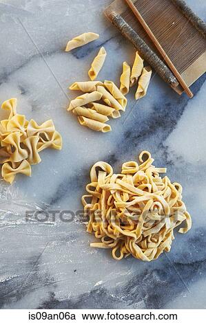 Stock Image - Freshly made pasta varieties on marble slab. Fotosearch