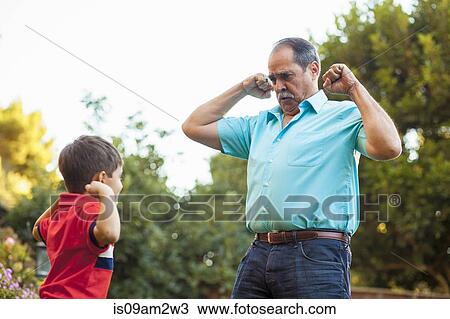 Grandfather and grandson flexing arms in garden View Large Photo Image Stock Image - Grandfather and grandson flexing arms in garden. Fotosearch