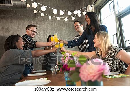 Stock Photo - "Group of friends around table, raising glasses, making toast". Fotosearch