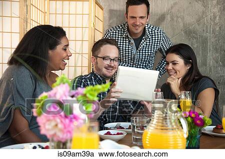 "Group of friends at dinner table, looking at digital tablet screen" View Large Photo Image Stock Image - "Group of friends at dinner table, looking at digital tablet screen". Fotosearch