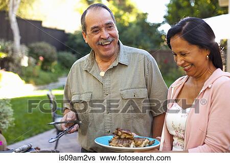 Husband and wife at barbecue grill in garden View Large Photo Image Stock Photograph - Husband and wife at barbecue grill in garden. Fotosearch