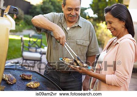Husband and wife at barbecue grill in garden View Large Photo Image Stock Photography - Husband and wife at barbecue grill in garden. Fotosearch