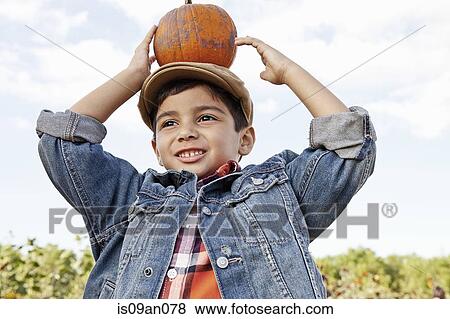 Low angle portrait of boy holding up pumpkin on his head View Large Photo Image Stock Photo - Low angle portrait of boy holding up pumpkin on his head. Fotosearch