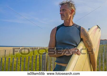 Mature male surfer carrying surfboard at beach View Large Photo Image Stock Image - Mature male surfer carrying surfboard at beach. Fotosearch