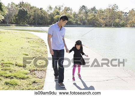 Mature man and daughter holding hands in park View Large Photo Image Stock Photograph - Mature man and daughter holding hands in park. Fotosearch