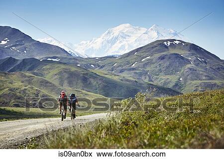 "Mid adult couple cycling on rural road, Mount McKinley, Denali National Park, Alaska, USA" View Large Photo Image Stock Photo - "Mid adult couple cycling on rural road, Mount McKinley, Denali National Park, Alaska, USA". Fotosearch