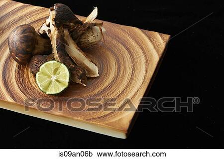 Stock Image - Mushrooms and lime slice on chopping board. Fotosearch