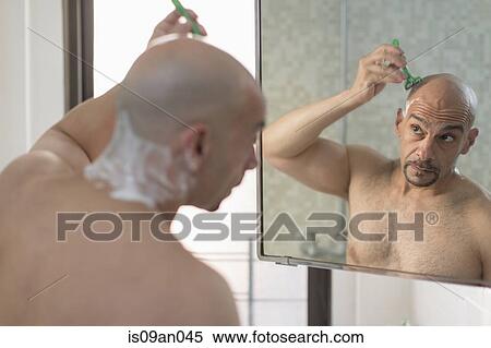 Over the shoulder view of mature man shaving his head in bathroom View Large Photo Image Stock Photography - Over the shoulder view of mature man shaving his head in bathroom. Fotosearch