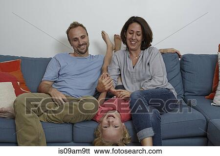 Stock Photograph - Parents with son sitting on sofa. Fotosearch