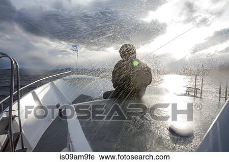 "Person in waterproofs sitting in front of boat sailing in rain storm, Ushuaia, Tierra del Fuego, Argentina" View Large Photo Image Stock Image - "Person in waterproofs sitting in front of boat sailing in rain storm, Ushuaia, Tierra del Fuego, Argentina". Fotosearch
