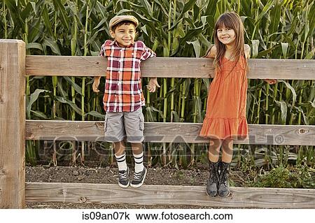 Portrait of boy and girl standing and holding onto field fence View Large Photo Image Stock Image - Portrait of boy and girl standing and holding onto field fence. Fotosearch
